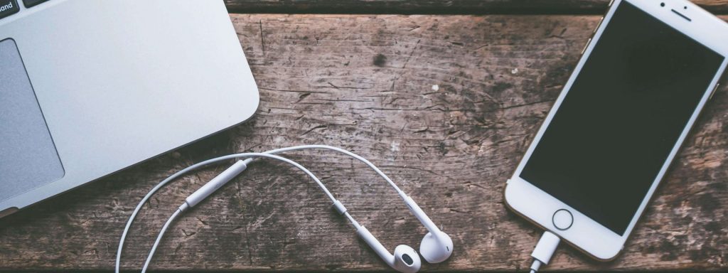 Mobiltelefon mit Kopfhörer und Teil von MacBook. Elektrosmog Bewusstsein.